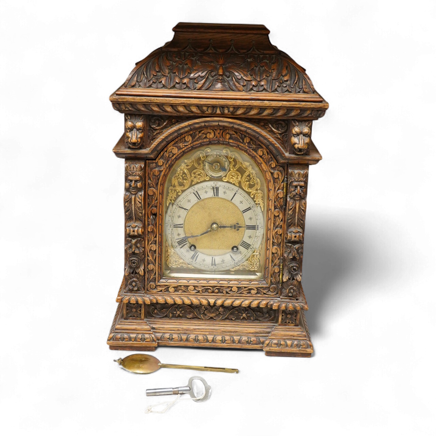 A Victorian carved oak bracket clock, the dial inscribed Goodsmiths Company, with pendulum and keys, 42cm high